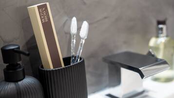A bathroom with a black soap dispenser, a black and white toothbrush holder, and a modern faucet.