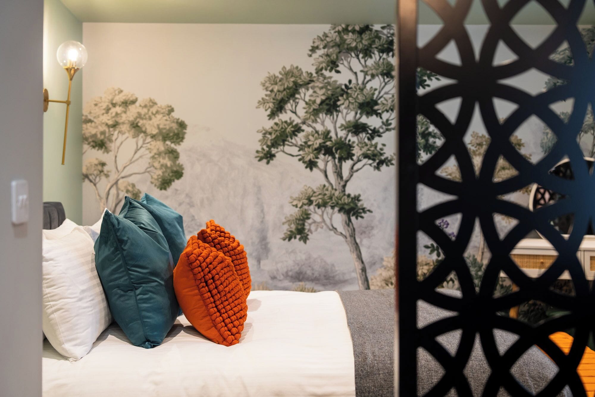 A bed with pillows, a wall mural, and a decorative partition.