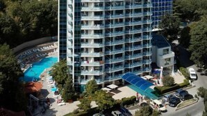 A multi-story hotel with a pool area, surrounded by greenery and hills. - Regina Hotel (Varna)