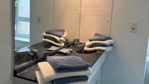 A bathroom with a double sink, a large mirror, and towels stacked on the counter. - Maison Familiale au Centre de Guingamp Animaux de Compagnies Acceptés (Guingamp)