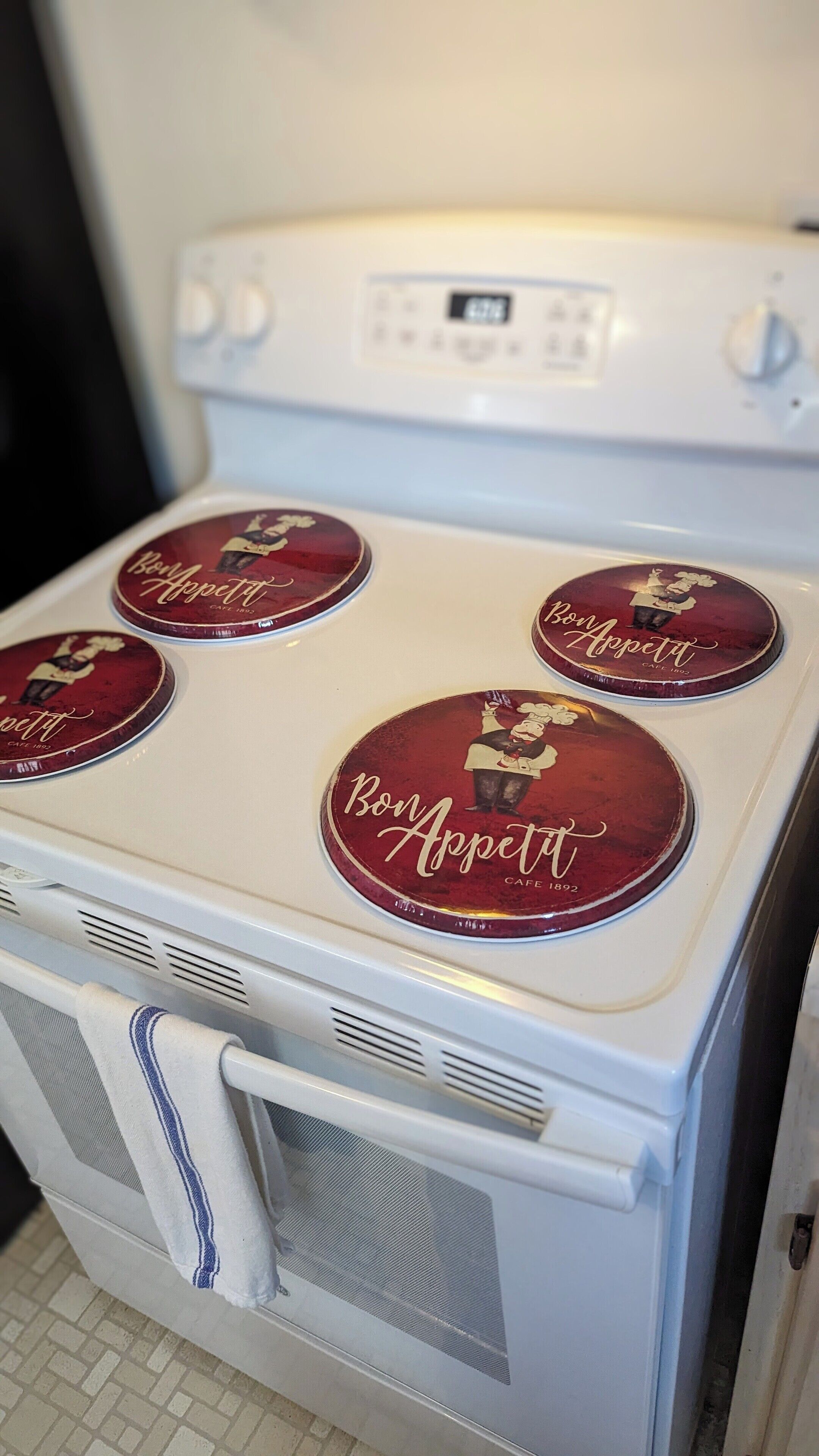 A white stove with four circular burners, each labeled 'Bon Appetit Cafe 1892'.