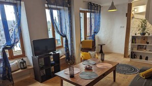 Una sala de estar con una mesa de madera, sofá y televisor.