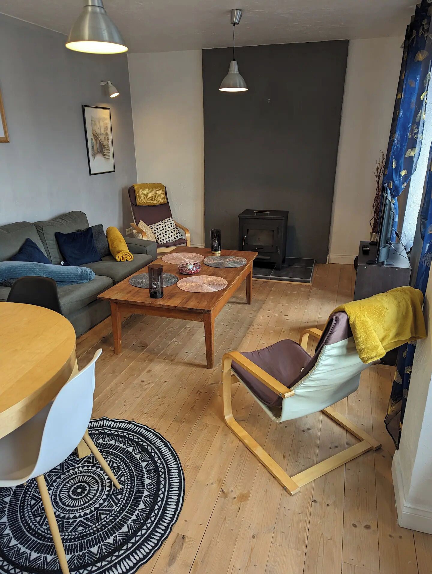 A living room with a sofa, a wooden coffee table, a patterned rug, a chair, and a fireplace.