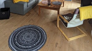 Una sala de estar moderna con un sofá gris, una mesa de centro de madera y una alfombra estampada.