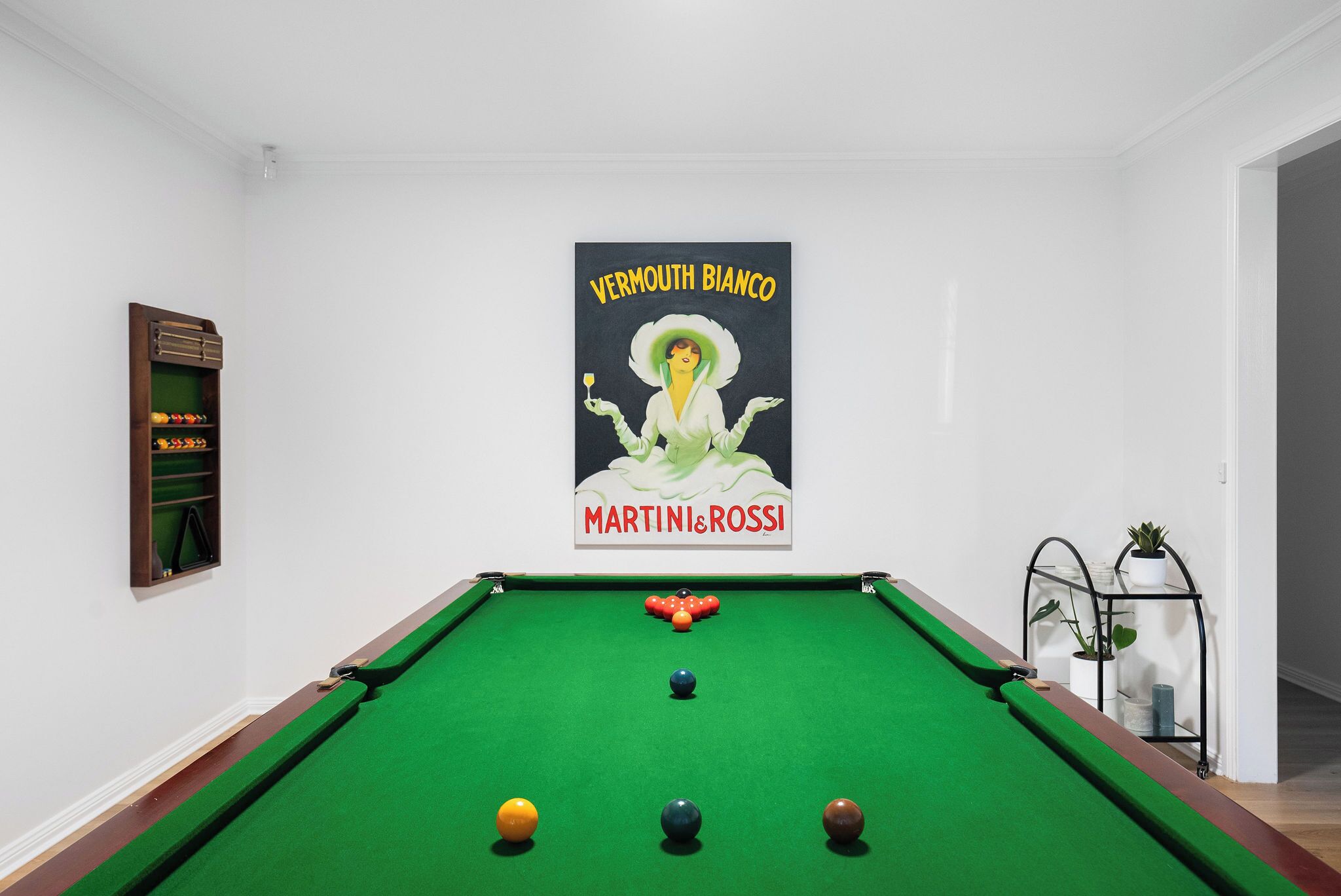 Una mesa de billar con bolas y un cartel con la imagen de una mujer.