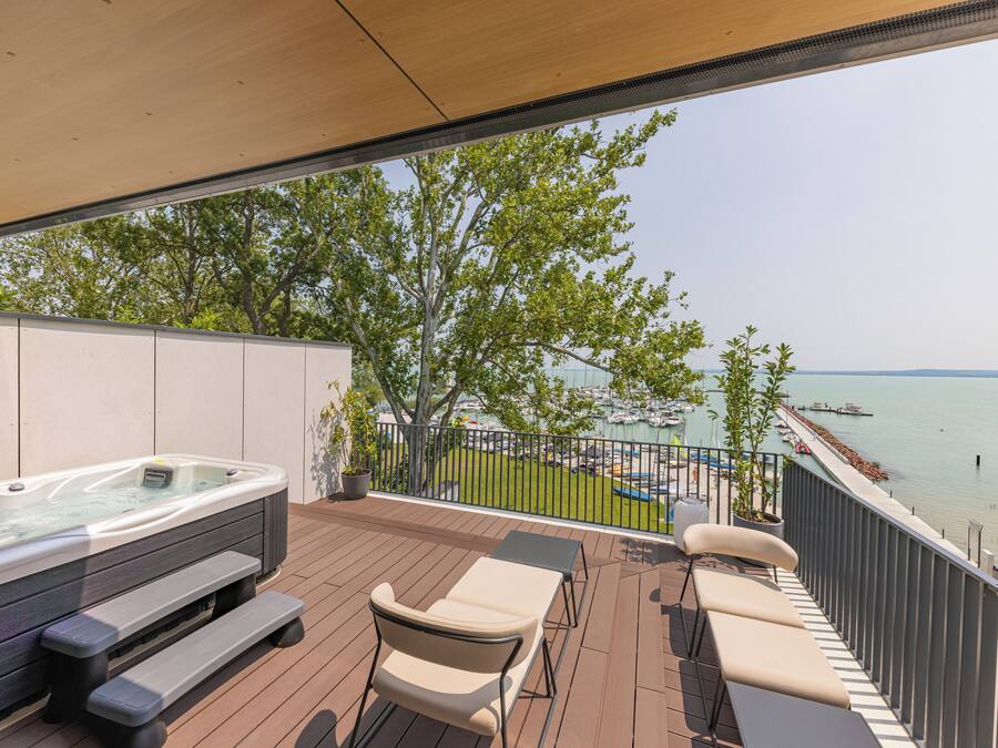 A balcony with a hot tub, lounge chairs, and a view of the water.