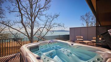 A hot tub with a clear view of the lake and mountains in the background.