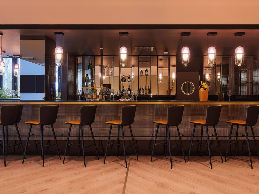 Una zona de bar con varios taburetes y una barra.