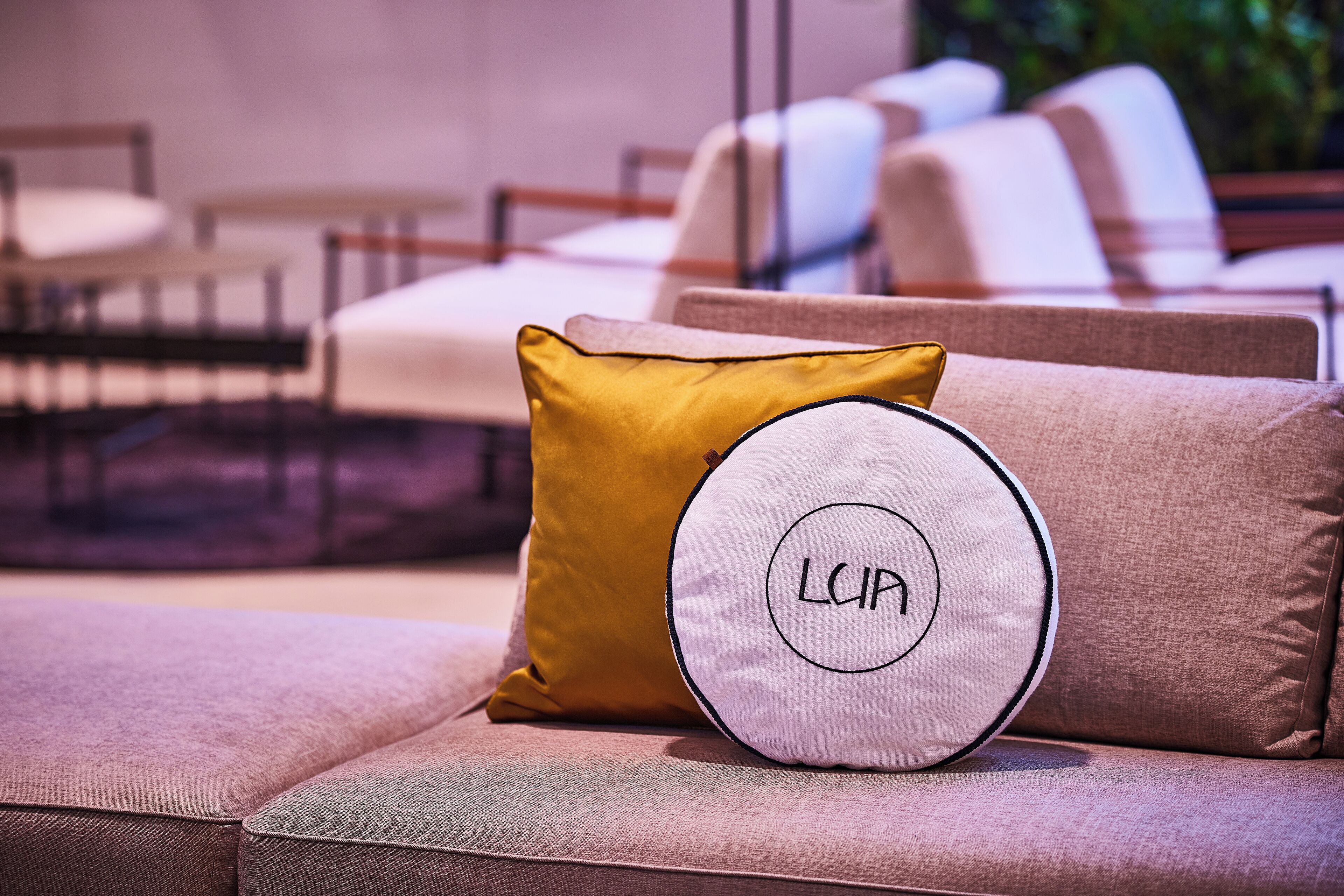 A modern living room with a sofa and two cushions, one with a circular design and the other with a solid color.