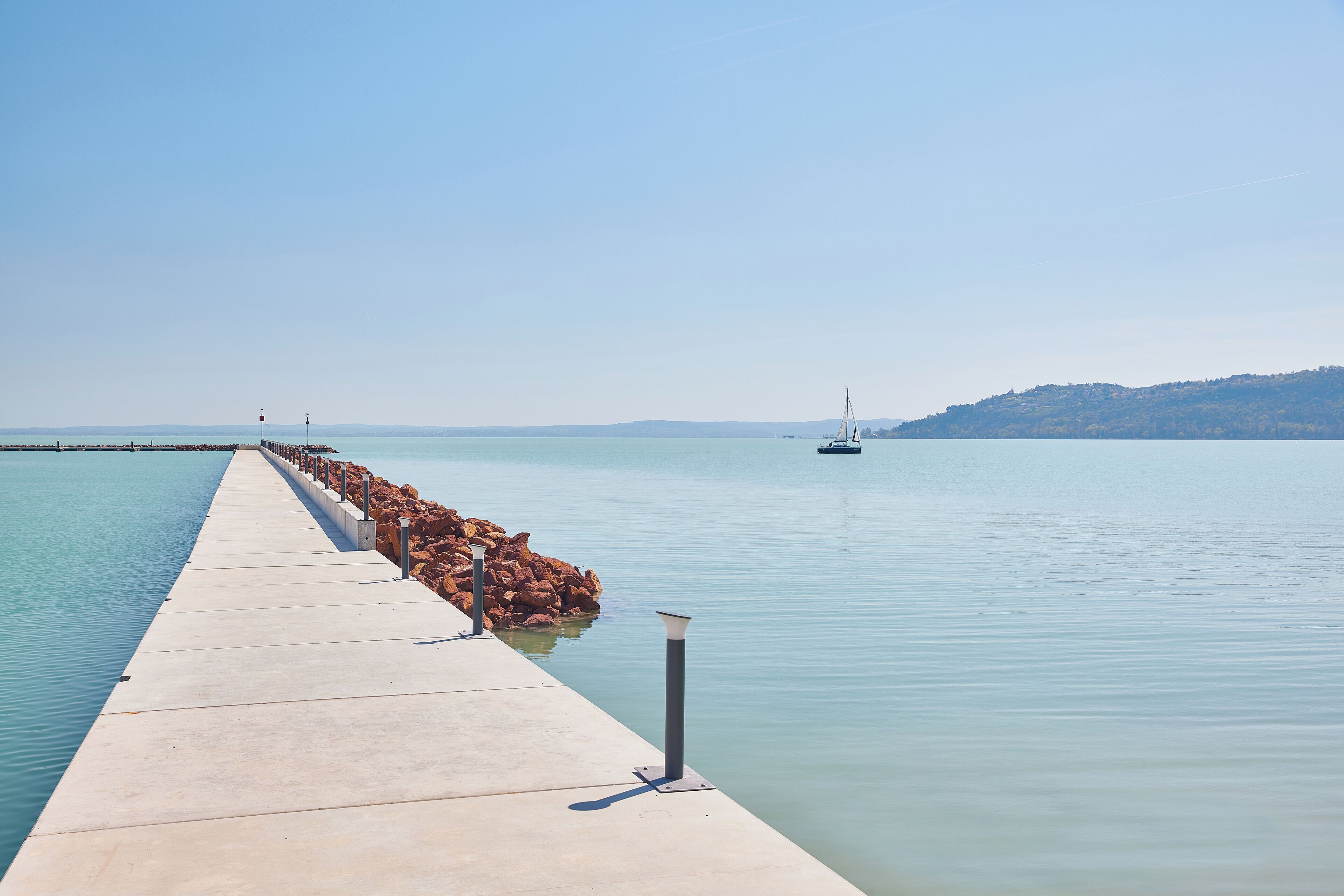 Un muelle de concreto se adentra en aguas tranquilas bajo un cielo despejado.