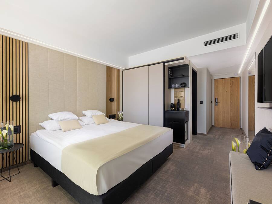 Ett modernt hotellrum med en stor säng, en sittgrupp och en TV.