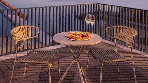 A terrace with a table set for two, overlooking a body of water and distant hills. - LUA Resort Balatonfüred (Balatonfured)
