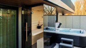 A modern spa area with a glass-enclosed sauna, a hot tub, and a wooden bench. - LUA Resort Balatonfüred (Balatonfured)