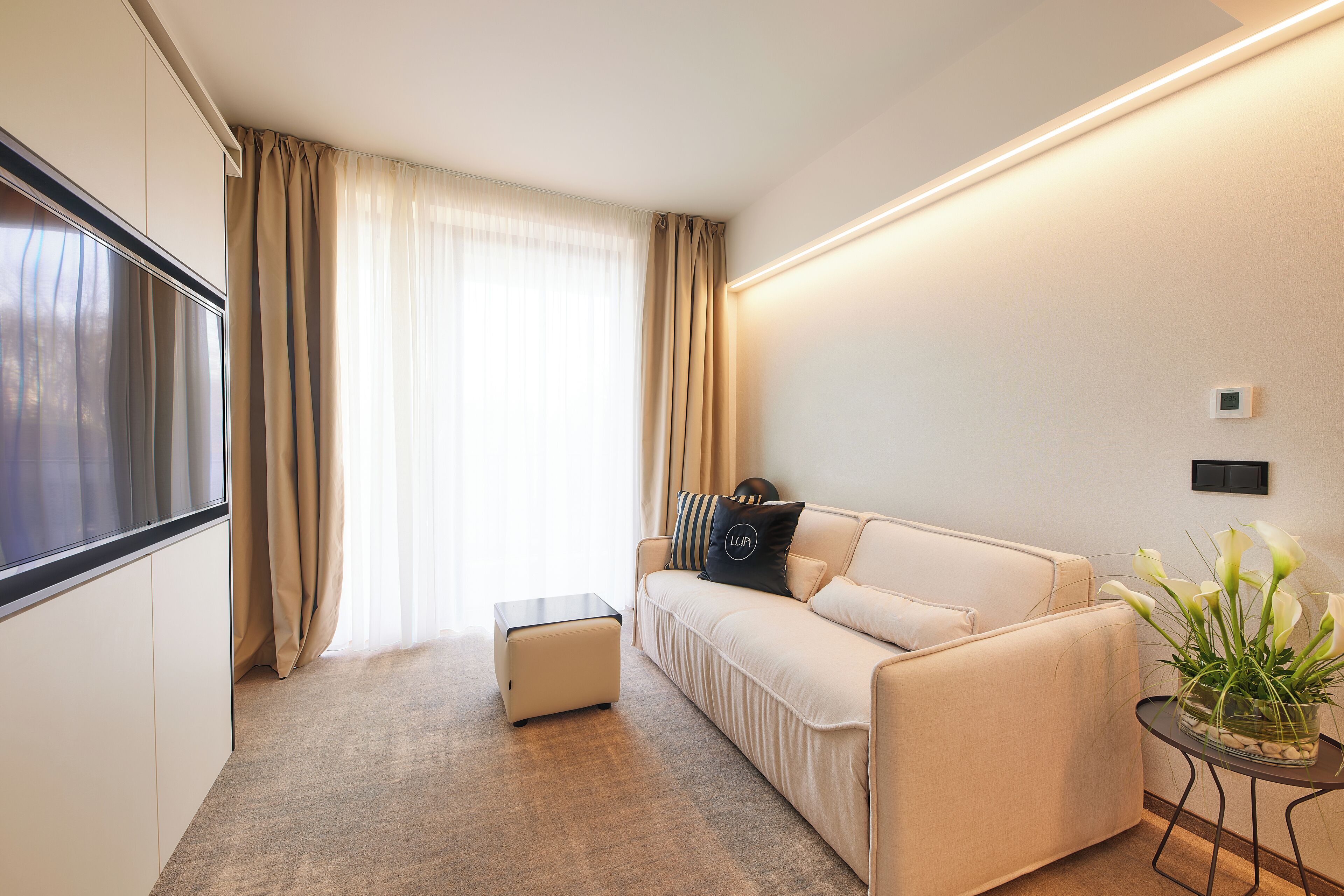 Una sala de estar moderna con un sofá, una mesita auxiliar y un ventanal con cortinas.