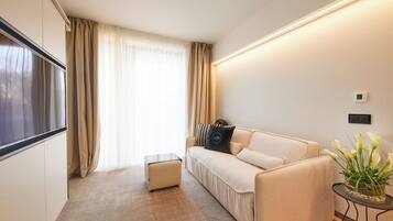 Una sala de estar moderna con un sofá, una mesita auxiliar y un ventanal con cortinas.