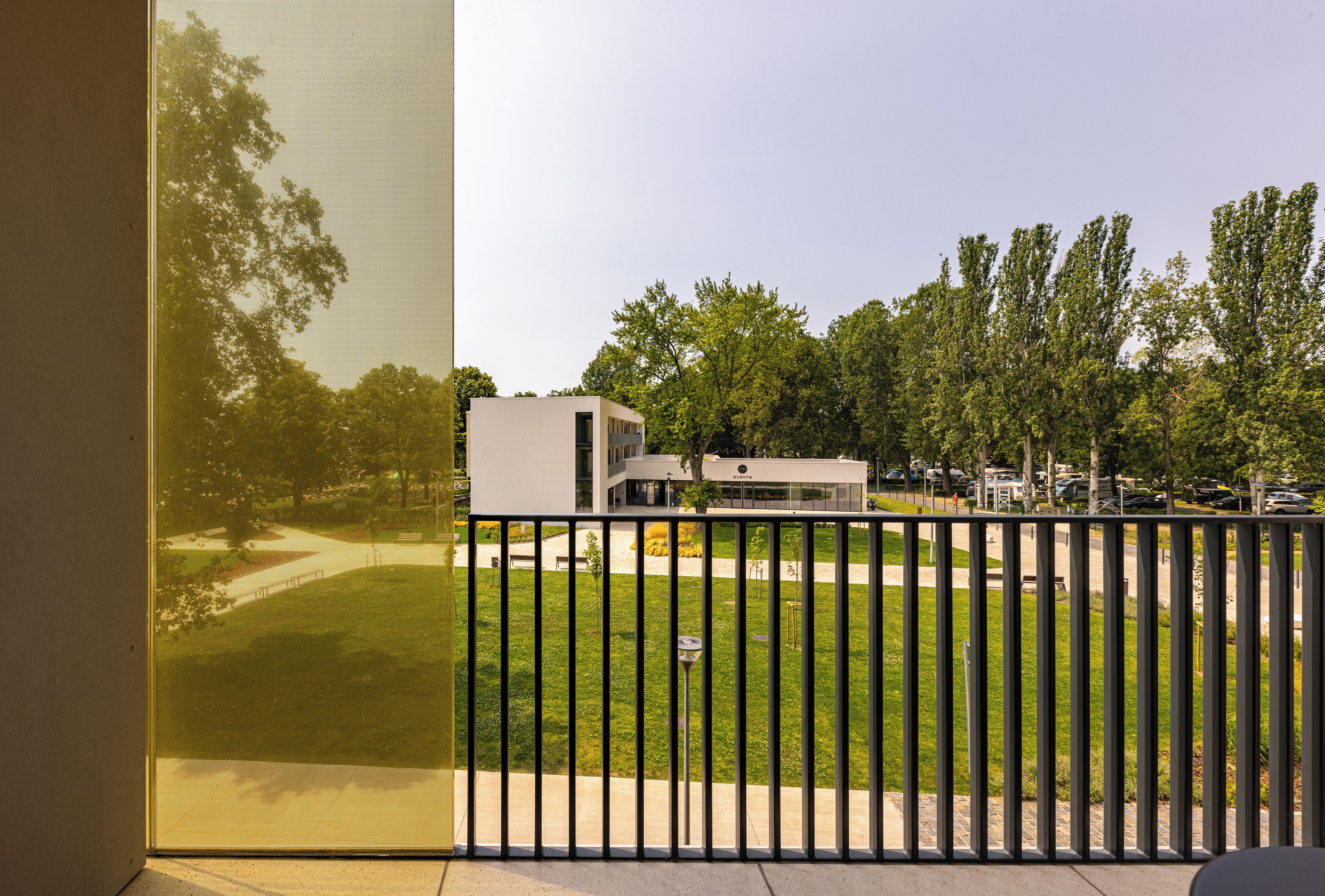 Un bâtiment moderne doté d’un toit plat et de grandes fenêtres, entouré d’une pelouse bien entretenue et d’arbres.
