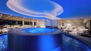 A modern indoor pool area with a circular hot tub, lounge seating, and a unique ceiling design. - LUA Resort Balatonfüred (Balatonfured)