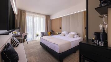 Habitación de hotel con una cama grande, un escritorio, una silla, un televisor y una cafetera.