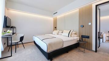 Une chambre d’hôtel moderne équipée d’un lit, d’un bureau avec une chaise, d’une télévision et d’une petite table avec un téléphone.