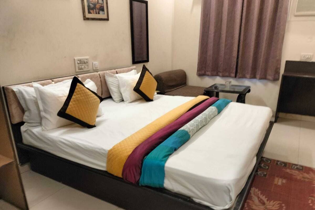 A neatly made bed with a variety of pillows and a colorful blanket.