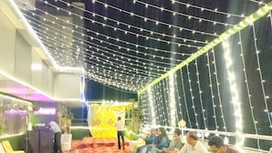A banquet hall with a red carpet, string lights, and a stage with a 'HAPPY BIRTHDAY' sign. - Hotel Jagat inn (Haridwar)