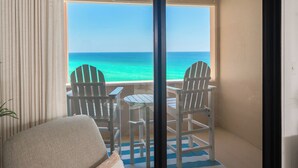 Un balcon avec deux fauteuils Adirondack, une petite table et une vue sur l’océan.