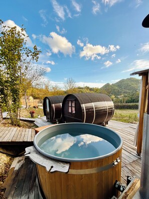 A hot tub on a wooden deck with two barrel-shaped structures in the background.