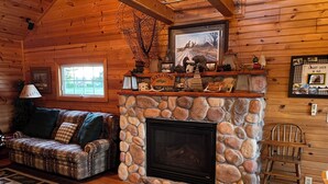 A cozy cabin interior with a stone fireplace, a wooden ceiling, a couch, and a rustic decor. - Little Lake Louise (Lucas)