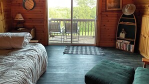 A cozy cabin with a loft bedroom, a balcony with chairs, a bookshelf, and a wooden ceiling. - Little Lake Louise (Lucas)