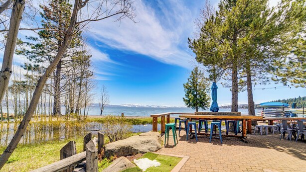 A lakeside patio with outdoor seating and a view of the lake and mountains.