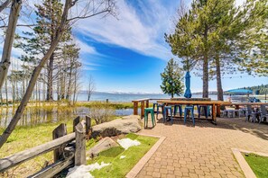 A lakeside patio with outdoor seating and a view of the lake and mountains.