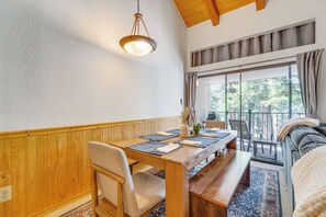 A dining area with a wooden table, chairs, and a bench. There is a hanging light fixture above the table. - Steps to Lake: Scenic Carnelian Bay Retreat (Carnelian Bay)