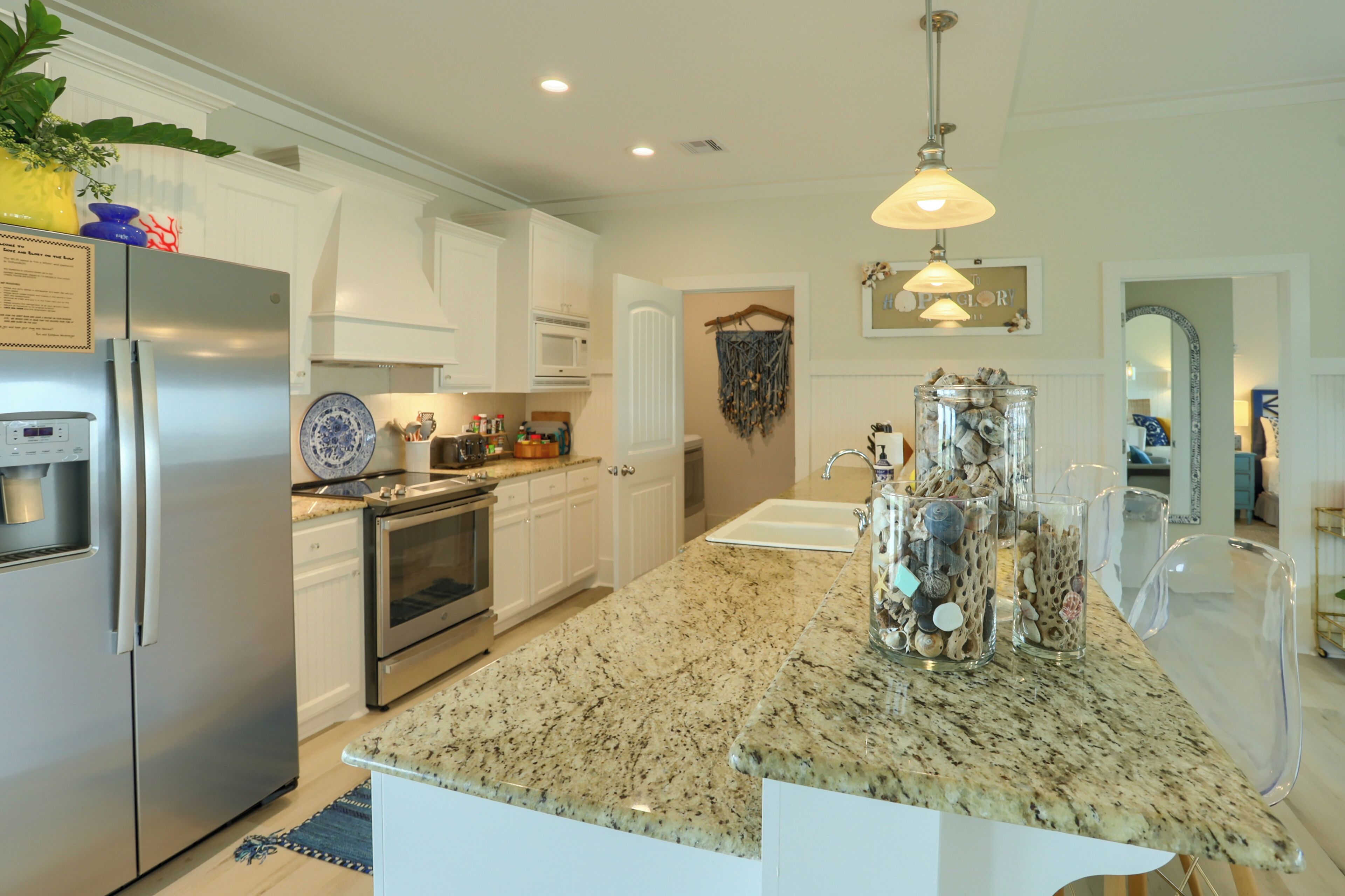 A modern kitchen with white cabinets, stainless steel appliances, and a granite countertop.