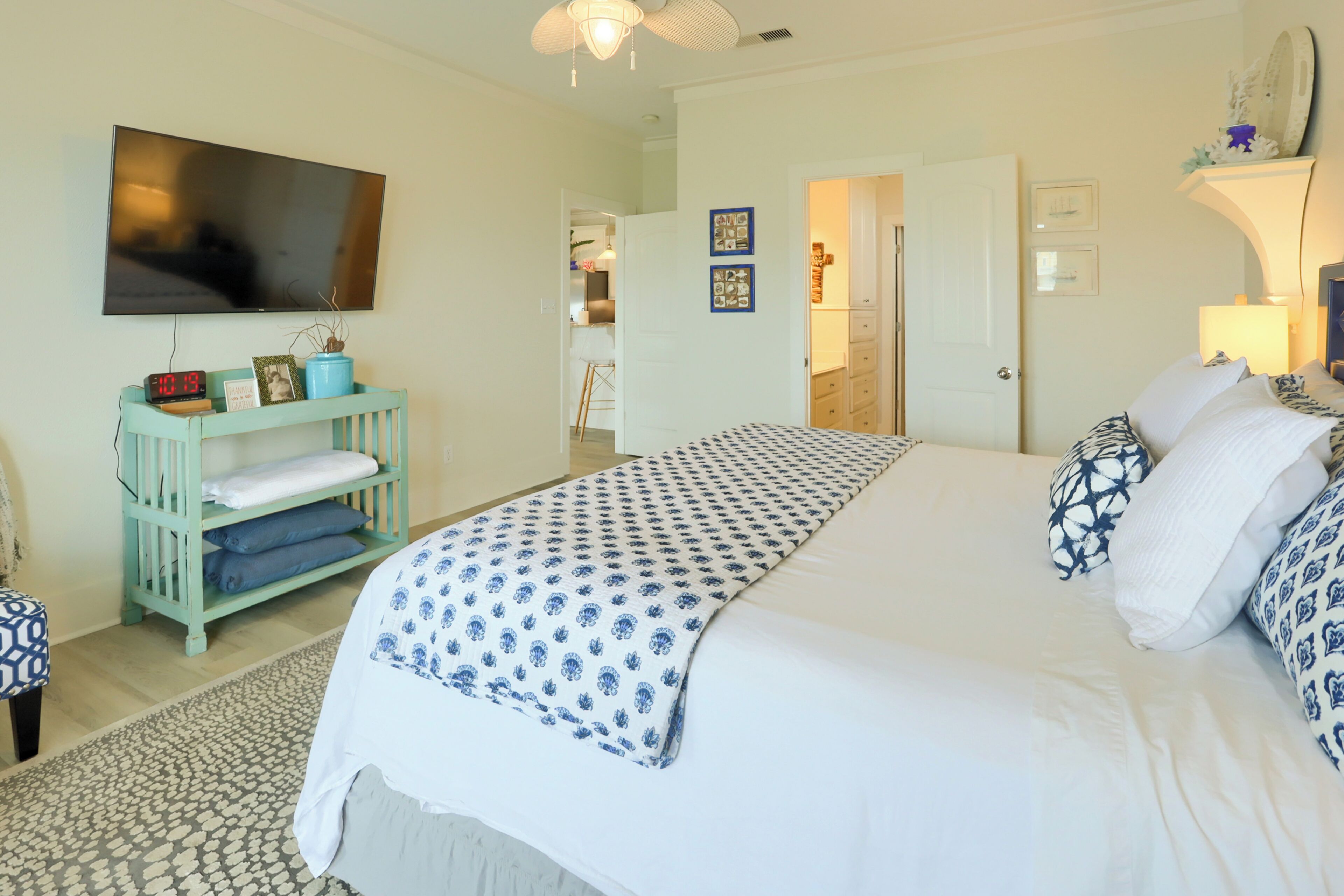 A bedroom with a large bed, a TV mounted on the wall, a bedside table, and a wardrobe.