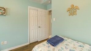 A bedroom with a bed, a door, and a wall decoration.