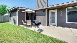 A residential backyard with a patio, a grill, and a wooden fence.