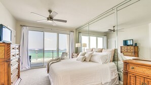 A spacious bedroom with a large bed, a ceiling fan, a television, and a view of the ocean through large windows. - Oceanfront Destin Condo With Pool & Beach Access (Destin)
