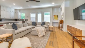 A modern living room with a sectional sofa, a wooden coffee table, and a TV mounted on the wall. - Spacious Austin Home: Near S Congress & Downtown! (Austin)