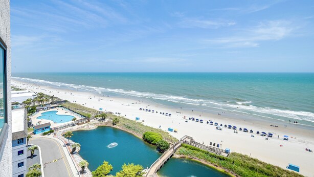 A beach view with a swimming pool, beach umbrellas, and a pier. - Shore & Pool Access: Resort Condo in Myrtle Beach! (Myrtle Beach)