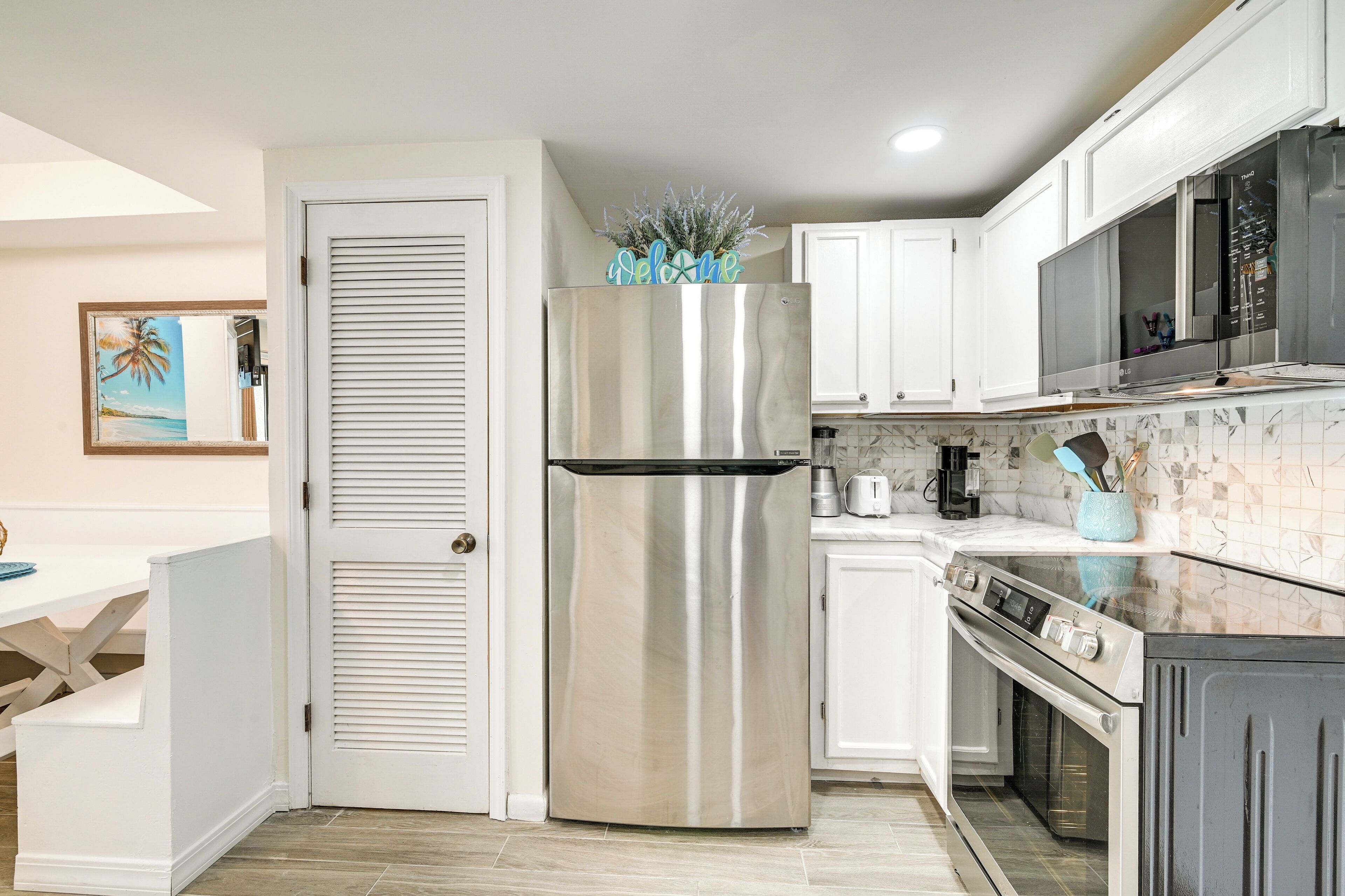 A kitchen with a stainless steel refrigerator, white cabinets, a microwave, and an oven.