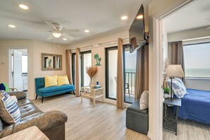 A modern living room with a ceiling fan, a sofa, a small table with decorative items, and a view through a glass door.