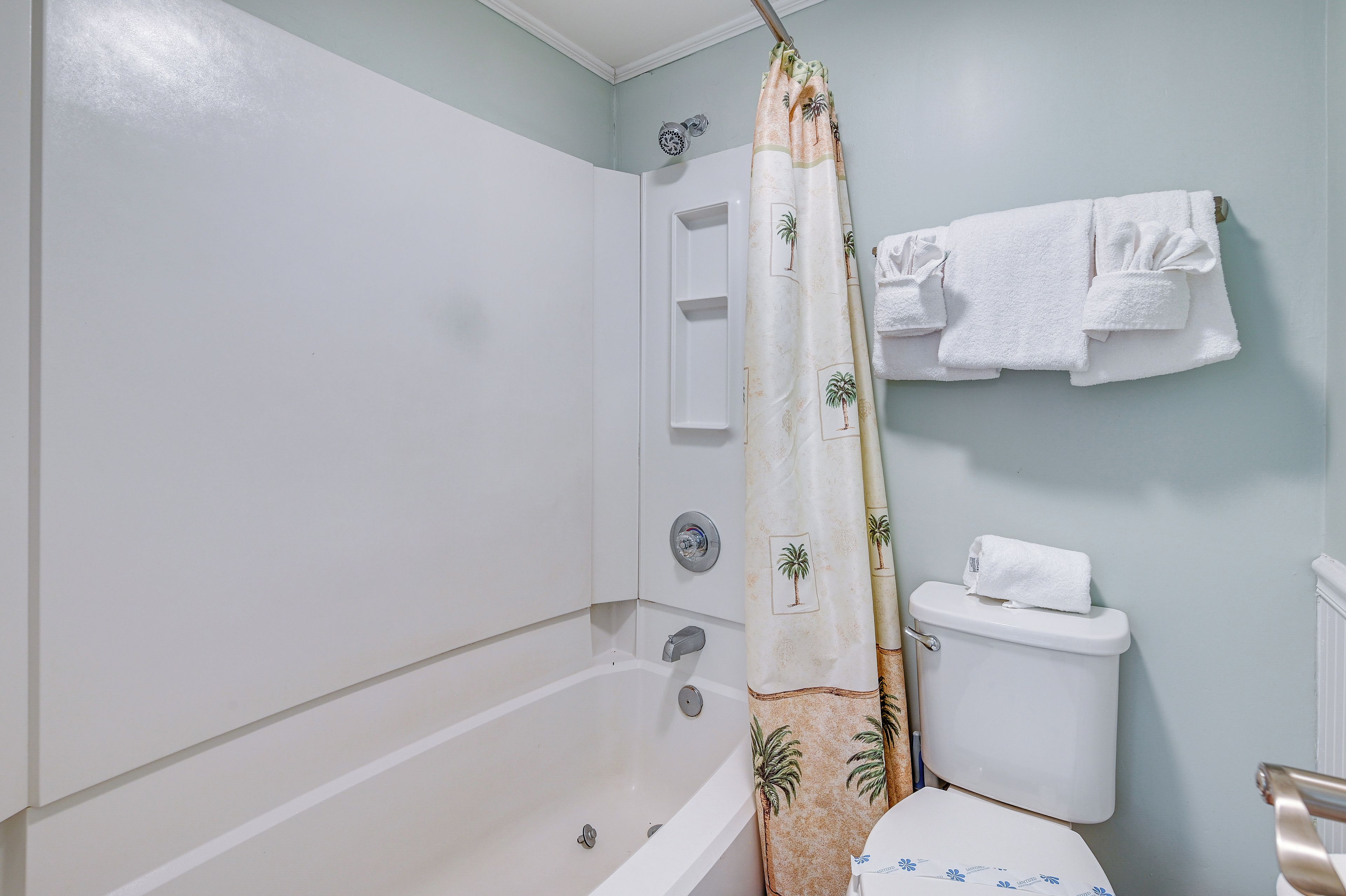 A bathroom with a bathtub, toilet, and shower curtain.