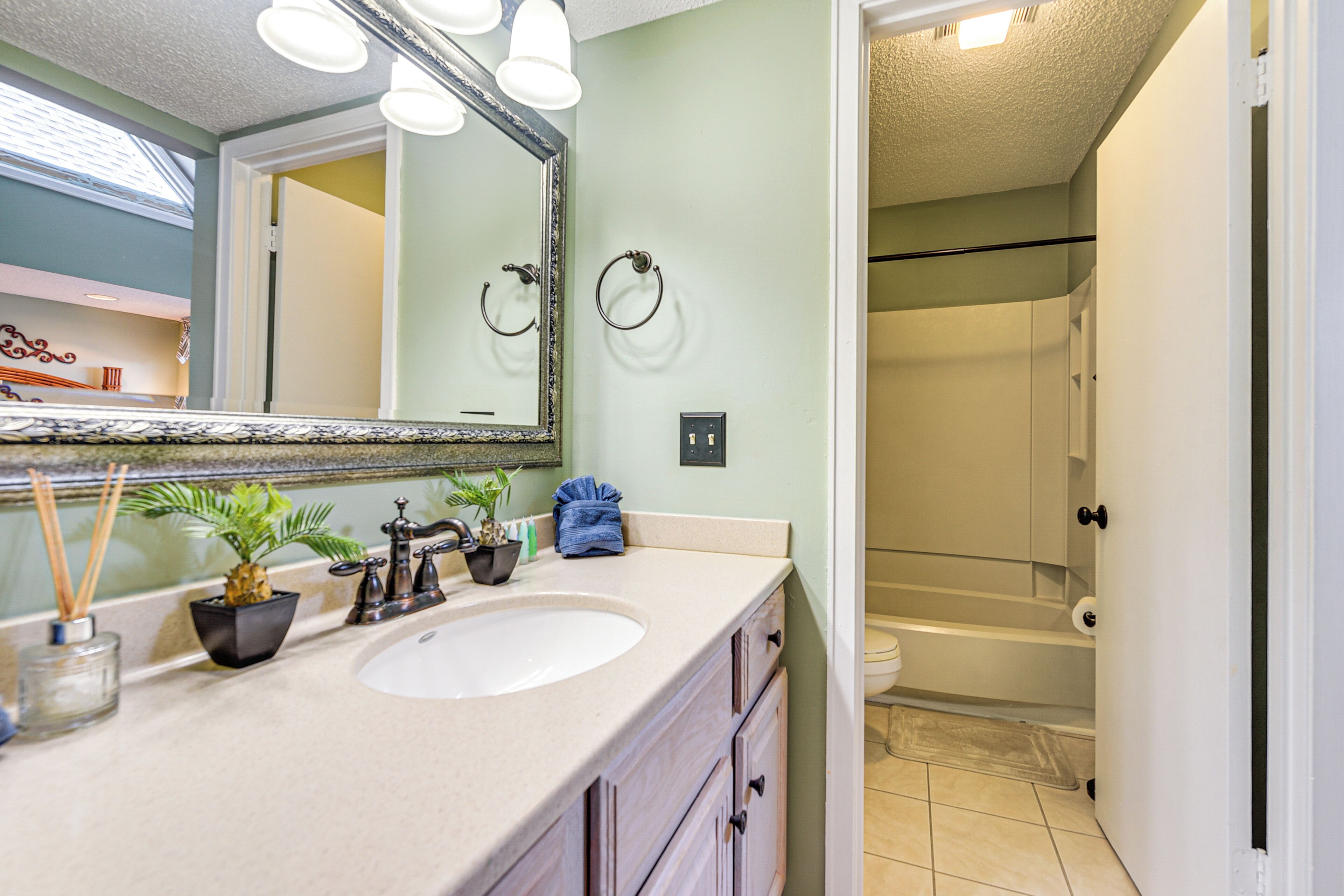 A bathroom with a sink, mirror, and towel ring.