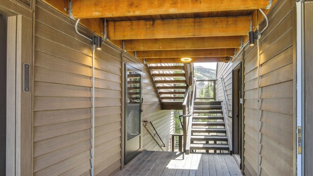 Un couloir intérieur en bois avec un escalier menant à un balcon.