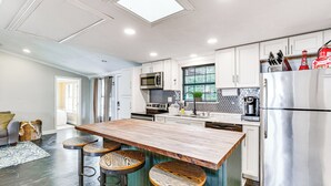 A modern kitchen with a central island, stainless steel appliances, and a view to the living area. - Private Dock & Deck: Eagle Mountain Lake Retreat! (Newark)