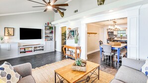 A spacious living room with a large flat-screen TV, a ceiling fan, and a dining area with a kitchen in the background. - Private Dock & Deck: Eagle Mountain Lake Retreat! (Newark)