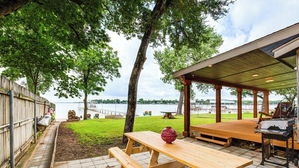 A picnic area with wooden benches and a grill, overlooking a lake. - Private Dock & Deck: Eagle Mountain Lake Retreat! (Newark)