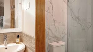 A bathroom with a white sink, a mirror, a marble wall, and a toilet. - Ara by Colombo Villas  (Colombo)