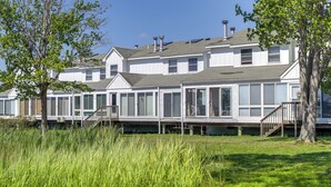 Une rangée de maisons blanches, dotées de grandes fenêtres et bordées d’une pelouse verdoyante.