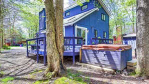 A blue cabin with a deck, surrounded by trees. - Hot Tub & Lake Beach Access: Tobyhanna Retreat! (Tobyhanna)